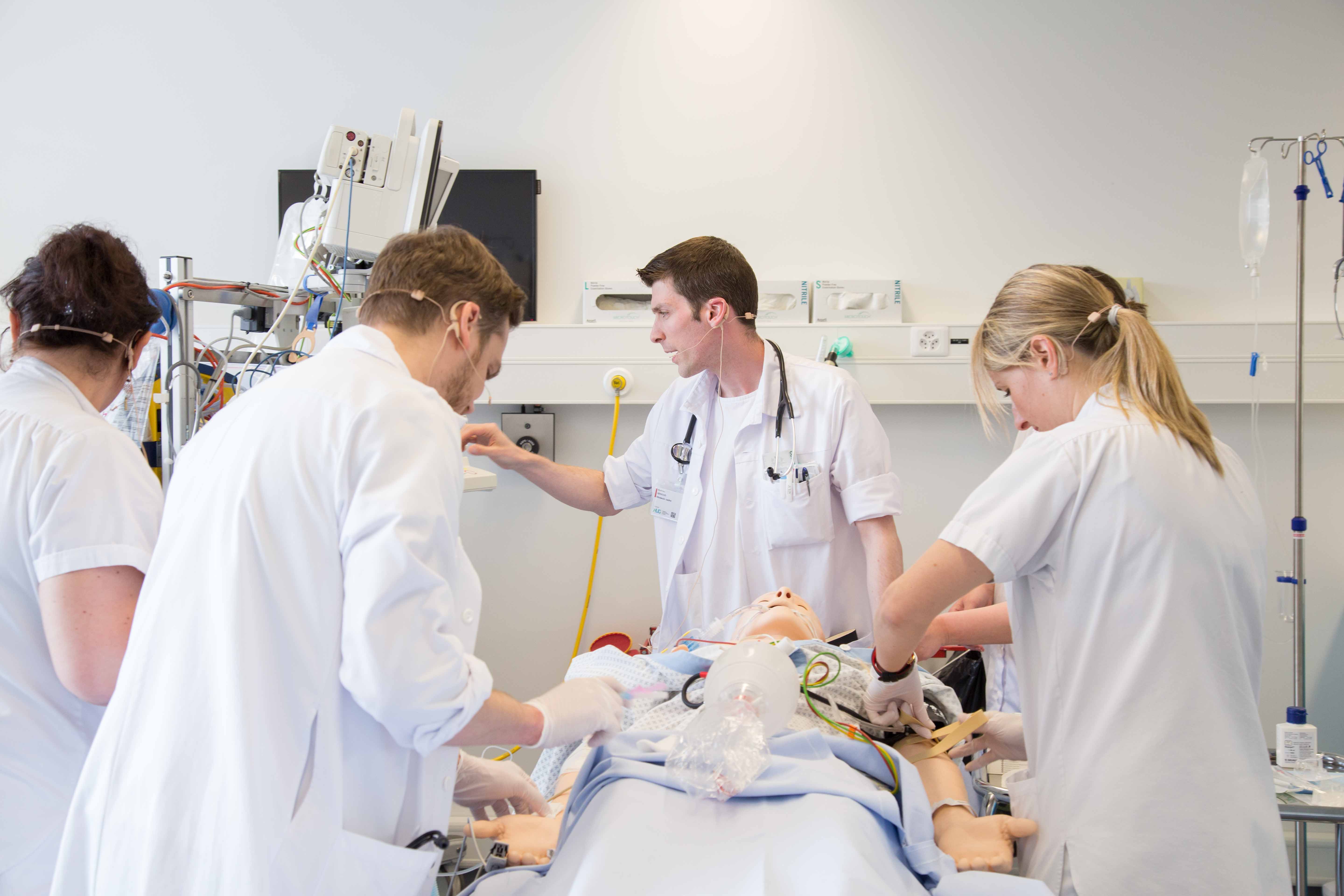 quatre étudiants travaillent en collaboration interprofessionnelle autour d'un mannequin haute fidélité